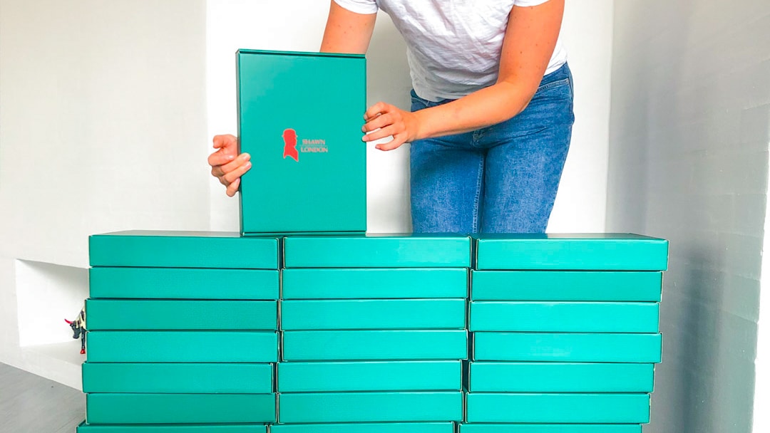Kvinde stabler grønne webshop-æsker med logo